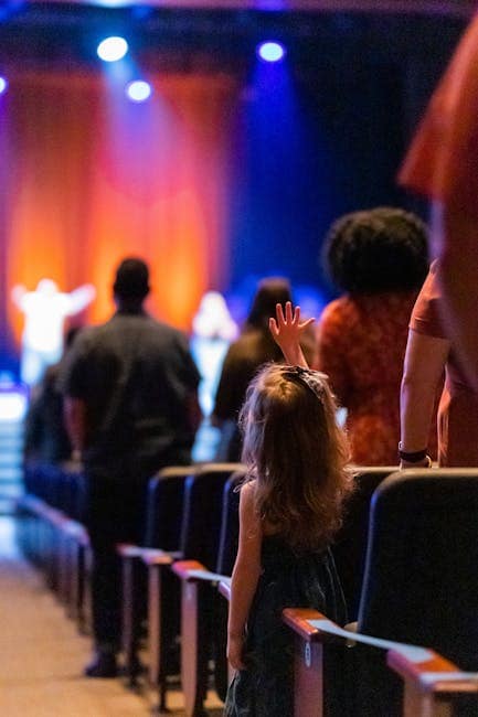 pexels photo 7626321 7626321 A young girl stands amidst a vibrant audience during a live concert indoors.